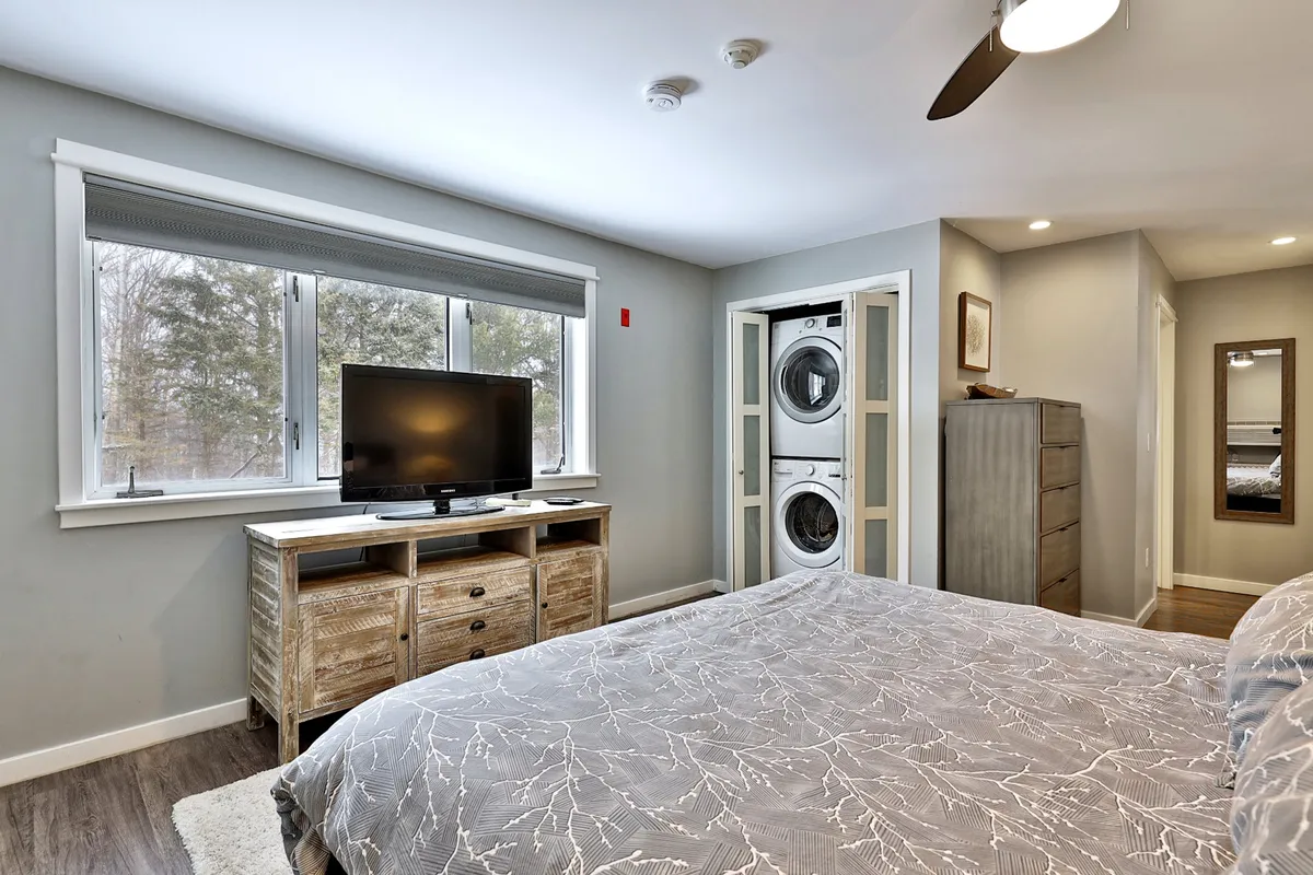 A bedroom scene that includes a comfortable bed with patterned bedding, a rustic wooden TV console, and an in-unit washer and dryer. This functional arrangement blends relaxation with convenience, ideal for extended stays and active getaways.
