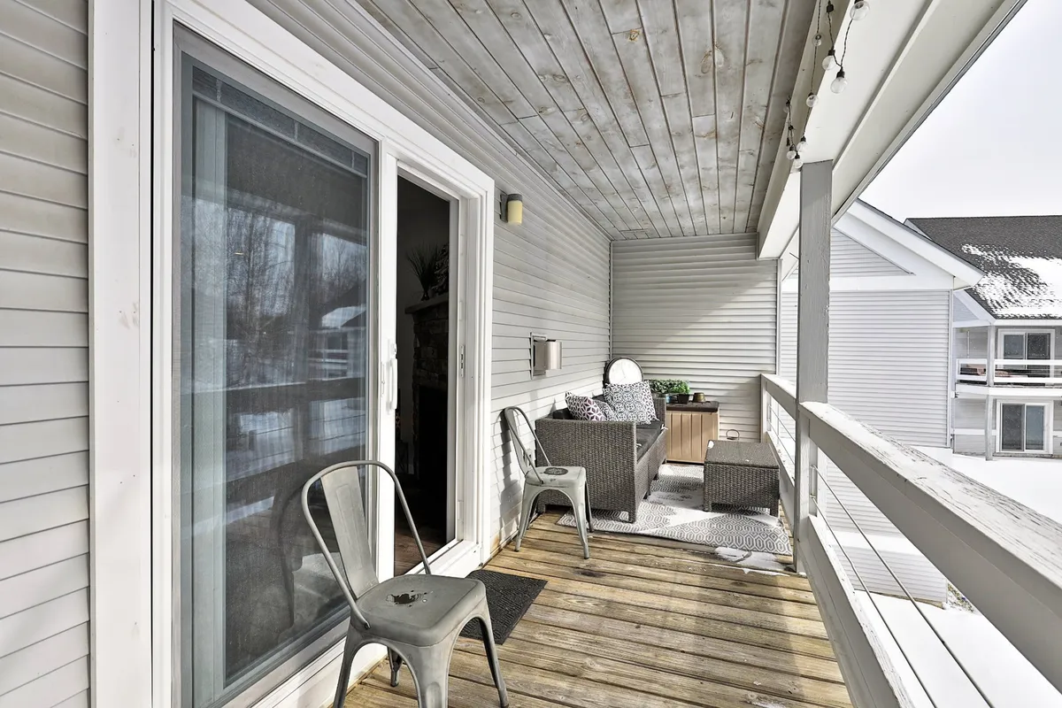 A cozy outdoor deck area with comfortable seating, decorative pillows, and a wooden railing. The setting is peaceful, ideal for relaxing, reading a book, or enjoying a morning cup of coffee while surrounded by natural scenery.